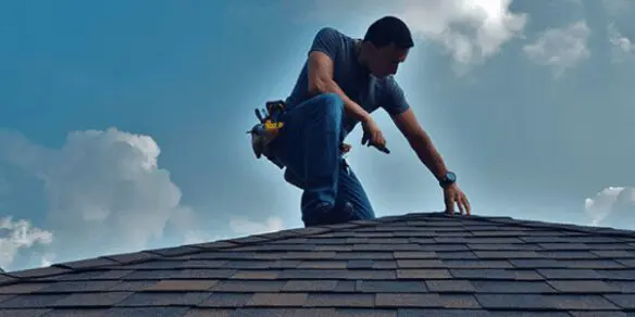 A man on top of a roof with tools.